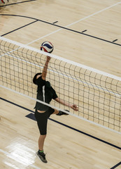 Volleyball player poking the ball over the net