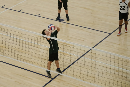 Volleyball player setting the ball by the net
