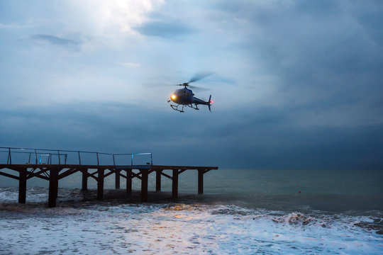 A helicopter is taking off during a sea storm.