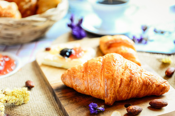 croissants with jam and coffee on wooden table