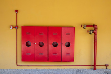 Hydrants, hose and fireman equipment on a yellow wall. 