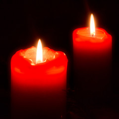 Zweiter Advent - Zwei brennende rote Kerzen vor schwarzem Hintergrund