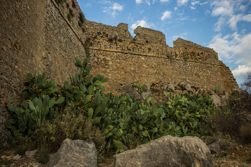 partly destroyed brick wall on rocky stone hill environment  on vivid blue sky background 