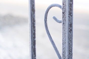 Frozen steel elements of the fence with hoarfrost