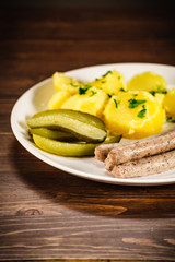 Boiled white sausages and vegetables on wooden table