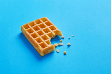 Single fresh waffle isolated on a blue background viewed from above. Copy space