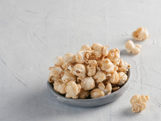 popcorn in gray craft trendy plate on gray concrete background. Moovie background with copy space. Top view or flat lay.