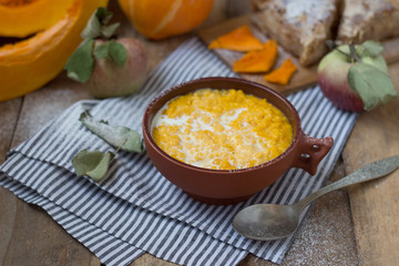 Pumpkin porridge with milk in a clay bowl with pumpkin and apple