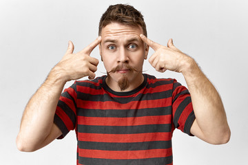 Emotional hipster guy with handlebar mustache expressing indignation, staring at camera and keeping...