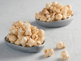 popcorn in gray craft trendy plate on gray concrete background. Moovie background with copy space. Top view or flat lay.