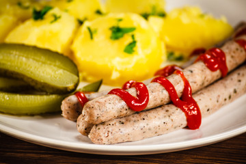 Boiled white sausages and vegetables on wooden table