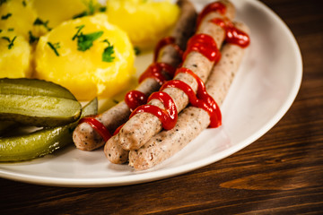 Boiled white sausages and vegetables on wooden table