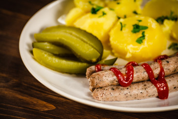 Boiled white sausages and vegetables on wooden table