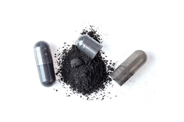 Activated charcoal capsule and powder isolated on white. top view