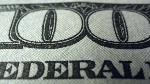 Panning over writing on 100 dollar bill in macro view.
