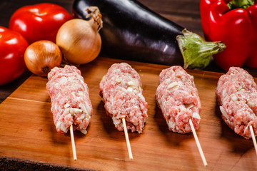 Raw hot dogs on cutting board and vegetables