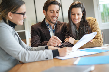 Attractive couple signing sales agreement with real estate agent