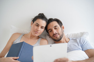 Isolated attractive couple reading and relaxing in bed