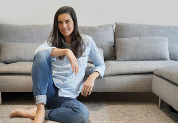 Fototapeta premium Isolated stunning brunette in denim on comfortable couch