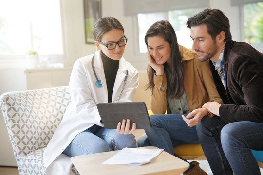 Happy Doctor With Couple Patients In Modern Office