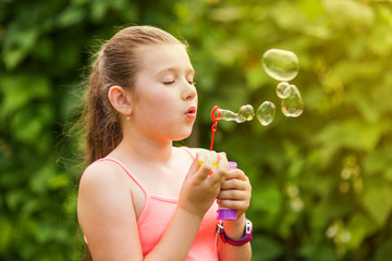 Portrait of a young girl blowing soap bubbles