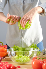 The girl prepares a salad of fresh vegetables. Vertical photo