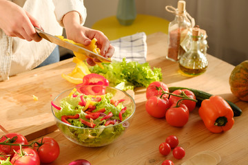 Girl cuts sweet pepper in vegetable salad. Cooking salad.