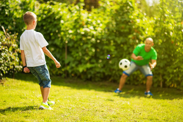 Obraz premium Son playing with his father footbal in a park, having fun