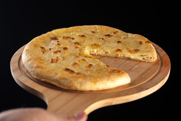 Georgian traditional food khachapuri on the wooden dish on black background
