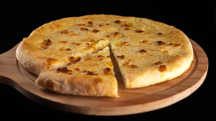 Georgian traditional food khachapuri on the wooden dish on black background