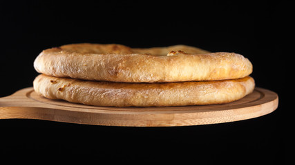 Georgian traditional food khachapuri on the wooden dish on black background