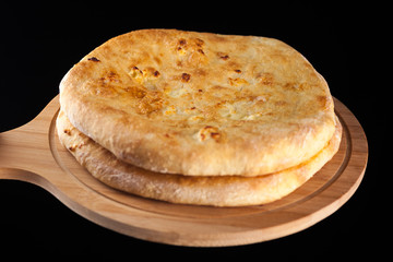 Georgian traditional food khachapuri on the wooden dish on black background