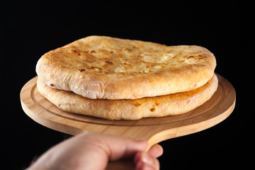Georgian traditional food khachapuri on the wooden dish on black background