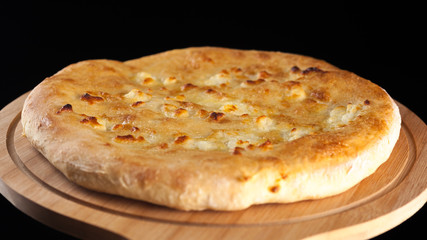 Georgian traditional food khachapuri on the wooden dish on black background