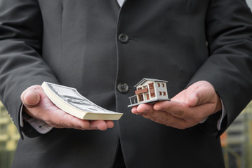 Miniature house toy and money in man's hands.Mortgage concepts. House and money