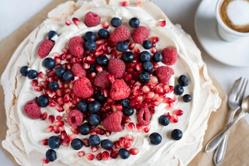 Meringue with raspberries, grapefruit and blueberries, espresso macchiato cup and vintage fork and spoon