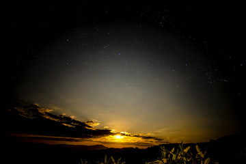 The moon is rising in the sky with stars.