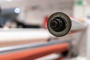 Operating a big printing machine and laminator, armed with red rolls and vinyl transparent film....