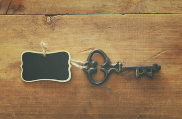 photo of antique key and empty blackboard tag over old wooden table.