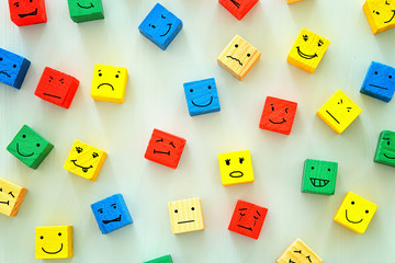 concept of Different emotions drawn on colorfull cubes, wooden background. - obrazy, fototapety, plakaty