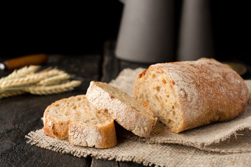 Fresh bread on sackcloth with wheat on a wooden background