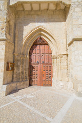 Obraz premium wooden door in ogival arch of Collegiate of San Miguel, or Saint Michael, from eleventh to sixteenth century, in Ampudia village, Palencia, Castile Leon, Spain, Europe