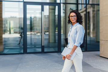 Woman walking on a street with digital tablet, looking away