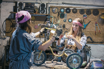 women mechanics repairing children bicycle in workshop