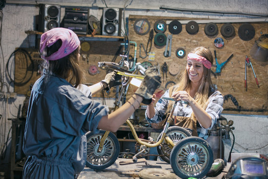 women mechanics repairing children bicycle in workshop