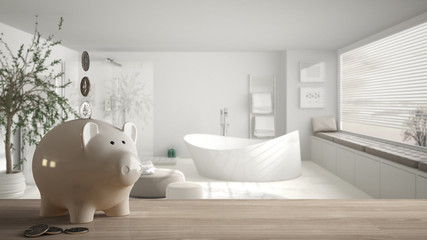 Wooden table top or shelf with white piggy bank with coins, modern minimal bathroom with bathtub,...