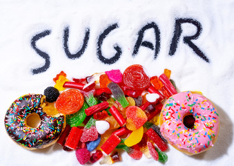 Close up of multicolor candies donuts and sweets over sugar in unhealthy food in children diet