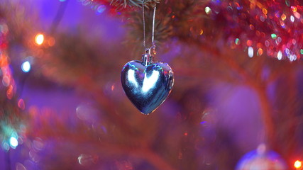 Silver heart on a red purple blurred background and spun bokeh, the concept of the New Year holiday and Christmas