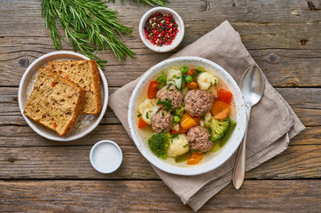 meatballs soup in white plate on old wooden rustic grey table, top view