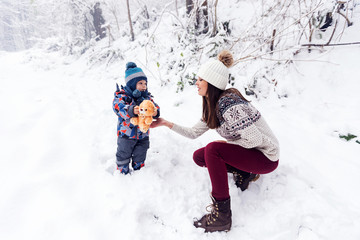 Mom and son playing with toy outside at winter day